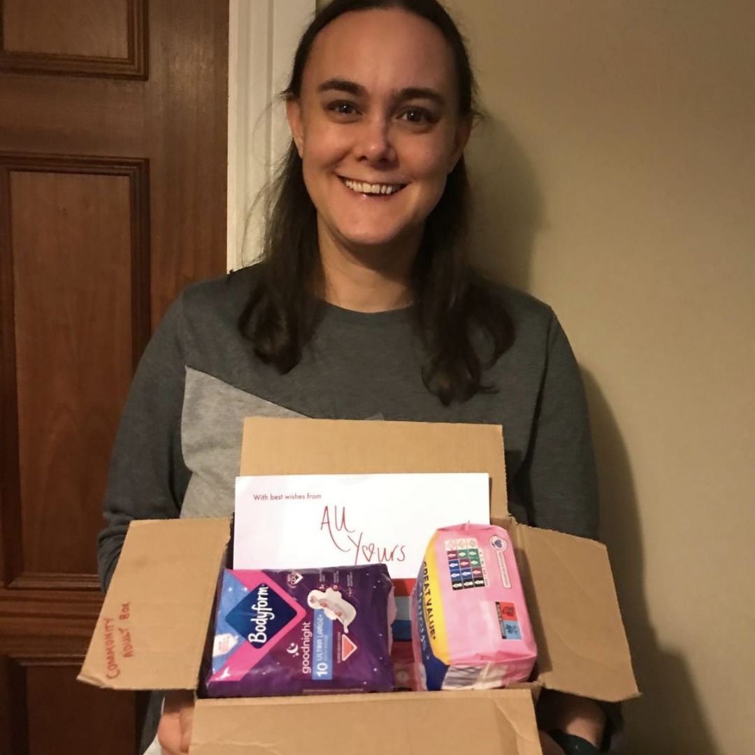 Caroline, founder of All Yours Period Box CIC, holding a community adult box of period products.