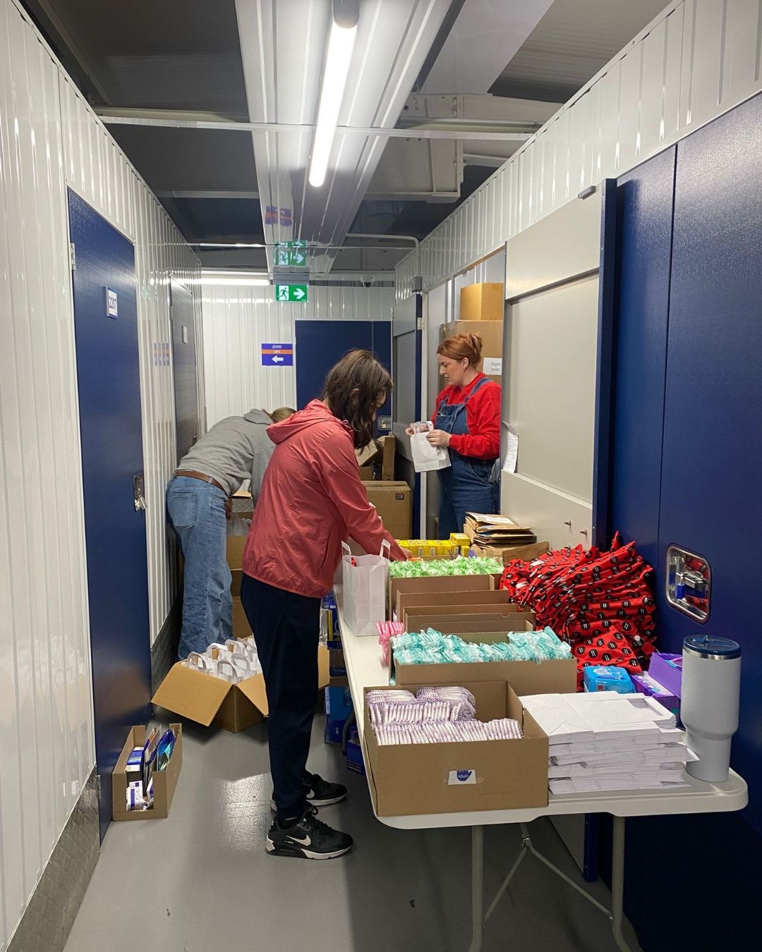 All Yours volunteers packing period product boxes inside a storage unit.